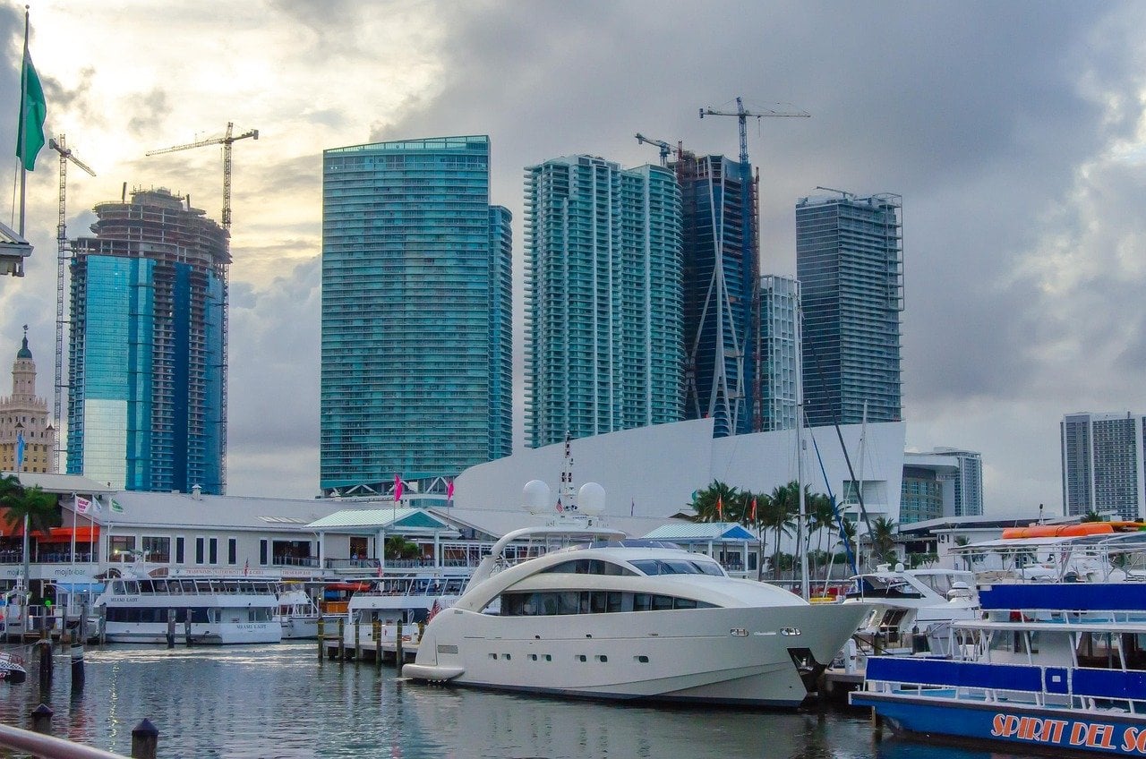 A sleek private charter yacht in a downtown Miami marina with the Biscayne Bay high-rise skyline behind it.